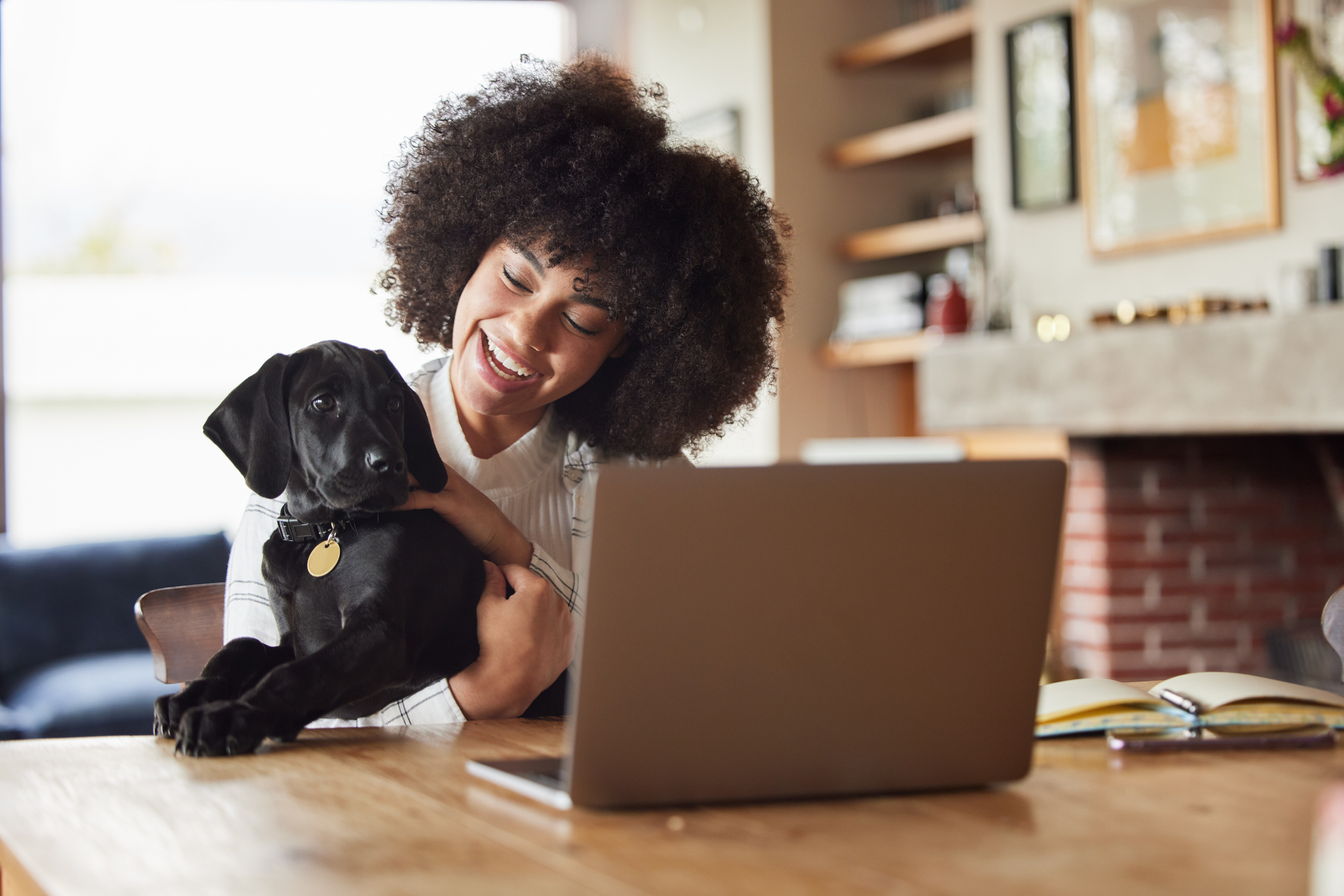 Girl smiling while holding black labrador puppy during virtual vet